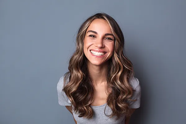 Joyful young white woman smiling and showing off her beautiful teeth and dental implants from Periodontal Surgical Arts in Austin, TX